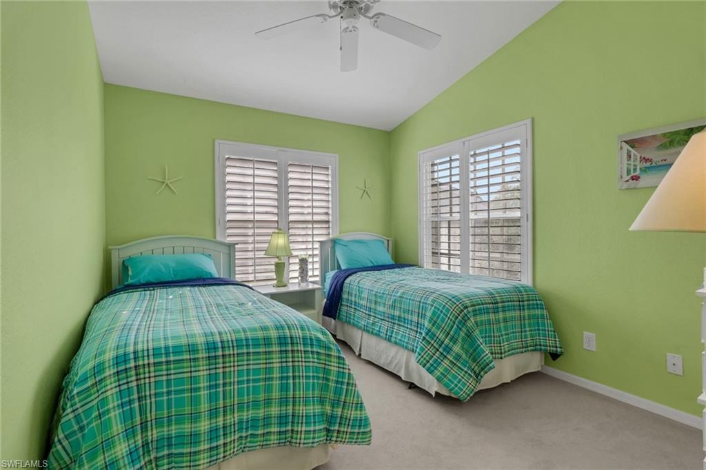 Bedroom with plantation shutters, lake view, light carpet,  and ceiling fan