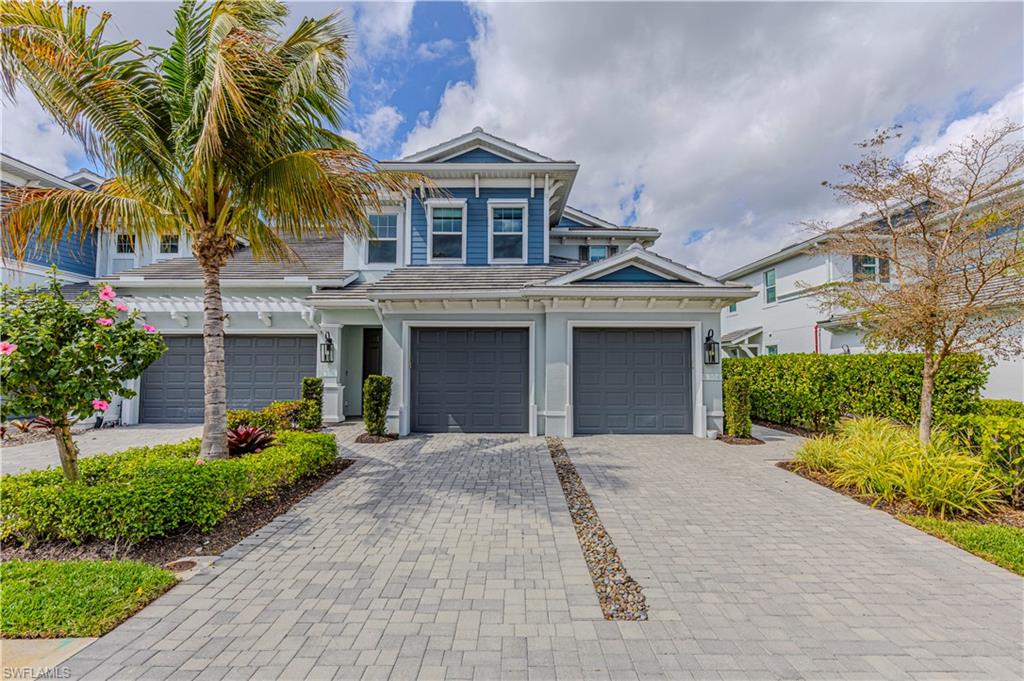View of front facade featuring driveway, attached garage & stucco siding