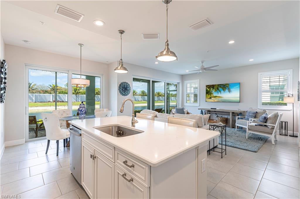 Kitchen featuring open floor plan, white cabinets, pendant lighting & an island w/ sink