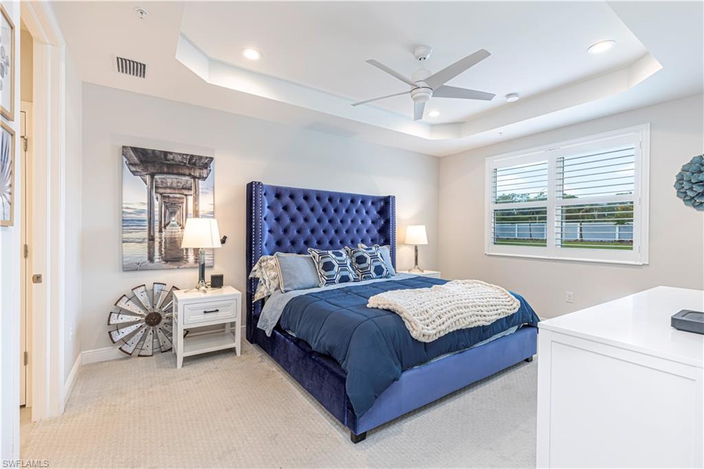 Bedroom w/ light colored carpet, ceiling fan, recessed lighting, & tray ceiling