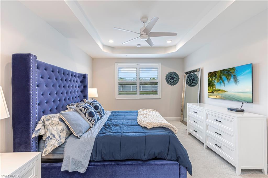 Bedroom w/ light colored carpet, tray ceiling, ceiling fan & recessed lighting