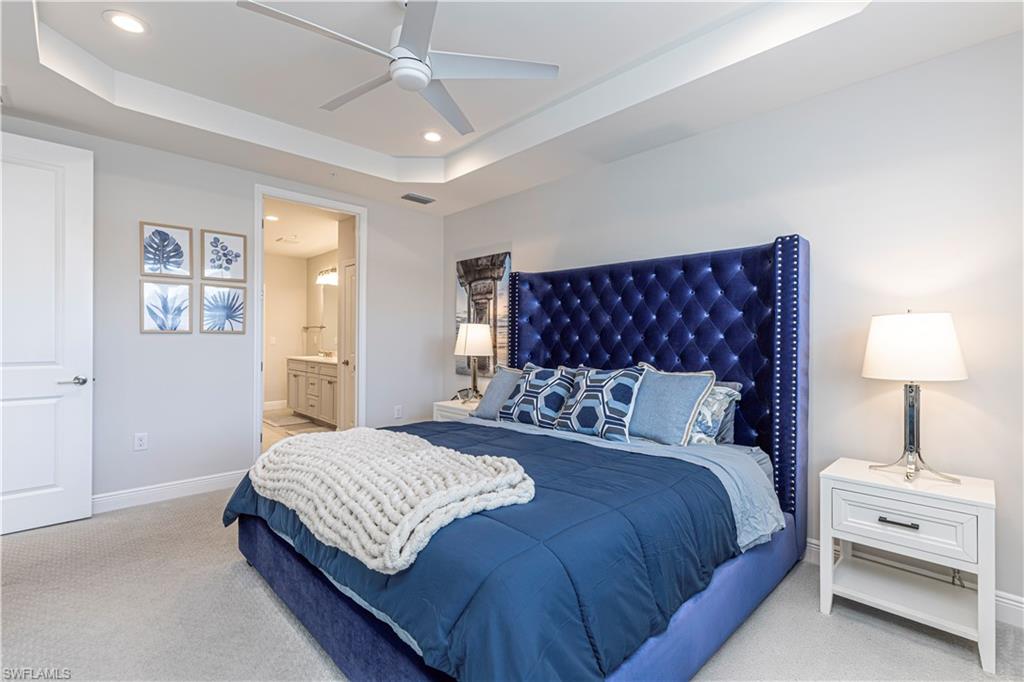 Bedroom featuring raised ceiling, recessed lighting, light carpet, ceiling fan & ensuite bathroom