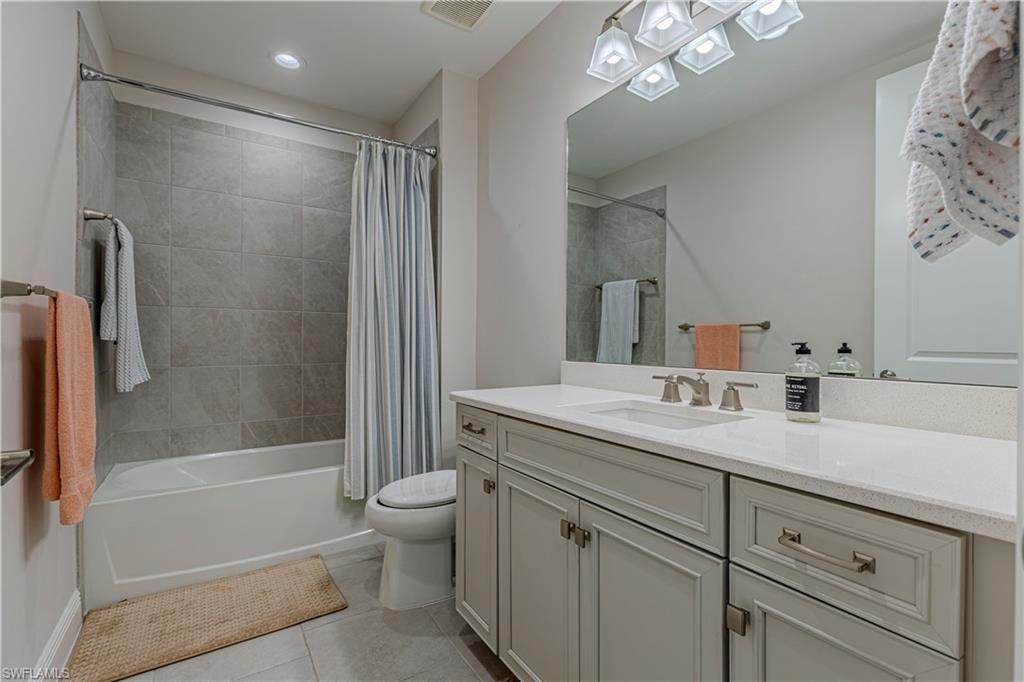 Bathroom w/ vanity, light tile patterned floors, and shower / bathtub combination w/ curtain