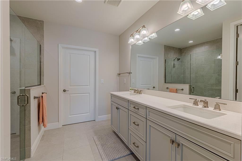 Bathroom w/ double vanity, a shower stall, and light tile patterned floors
