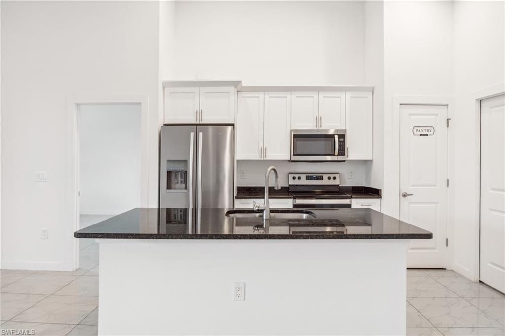 Kitchen with a center island with sink, white cabinets, and stainless steel appliances