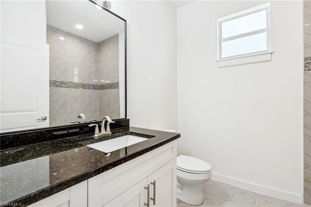 Bathroom featuring vanity, tiled shower, and toilet