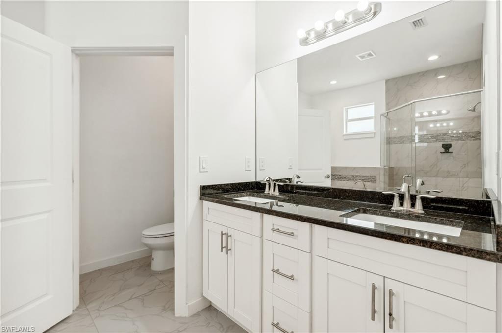 Bathroom with toilet, walk in shower, and vanity