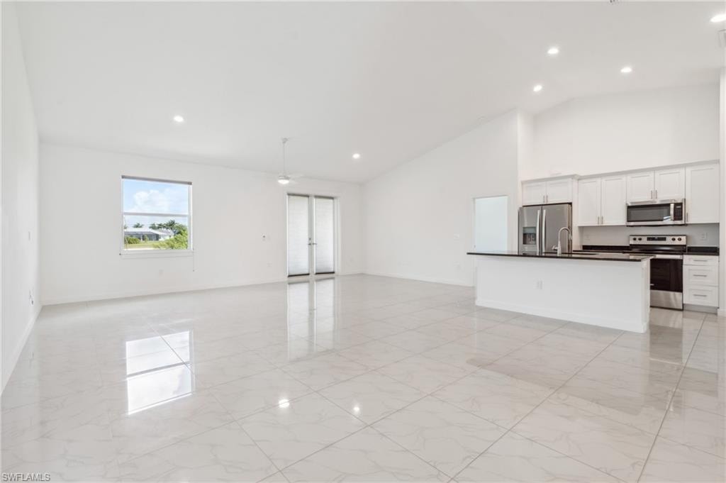 Unfurnished living room with high vaulted ceiling