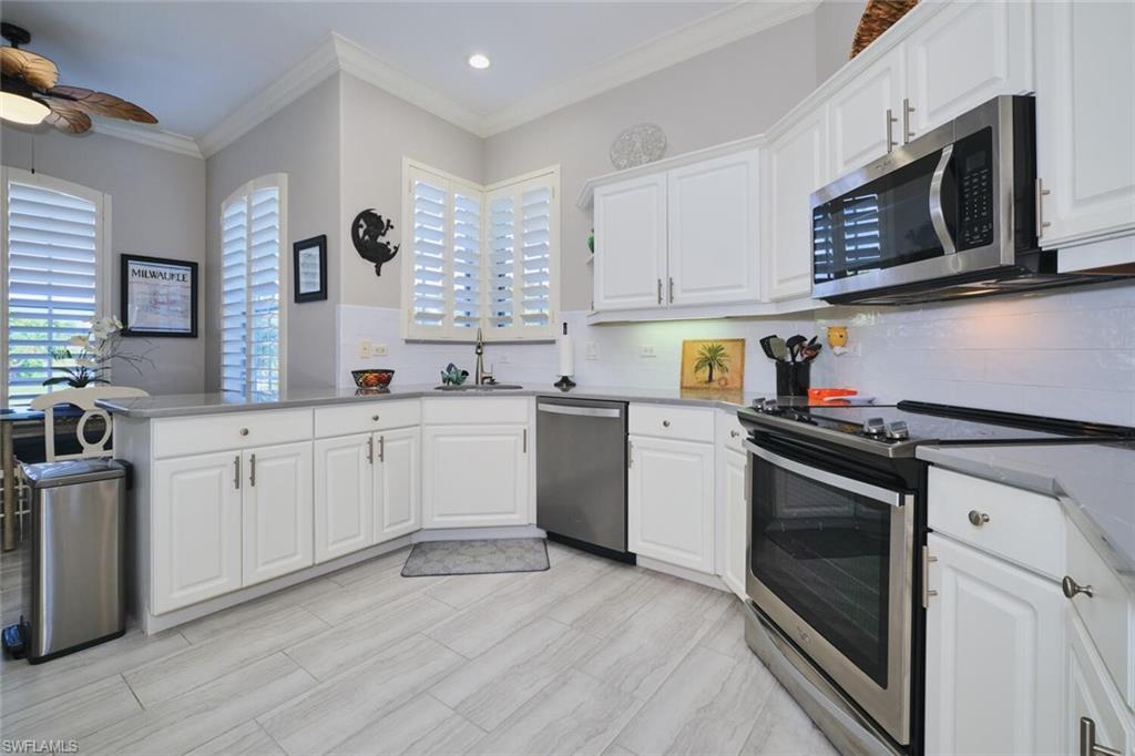 Kitchen featuring stainless steel appliances, white cabinets, ornamental molding, a peninsula, and ceiling fan