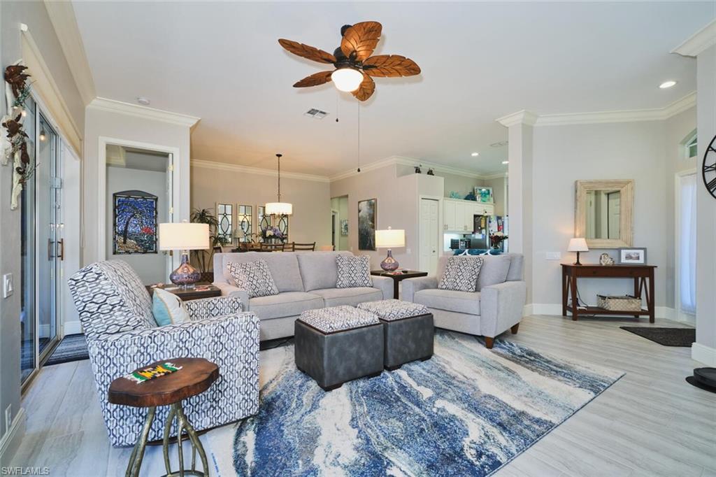 Living room with a ceiling fan, crown molding, and wood finished floors