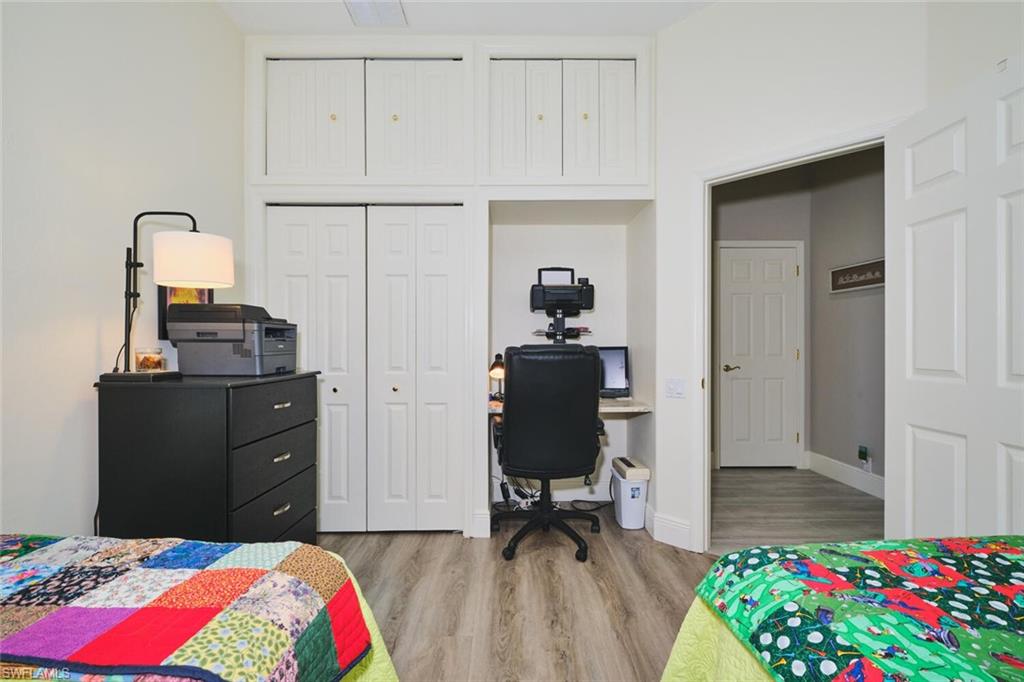 Bedroom with an office area, light wood-style flooring, and a closet