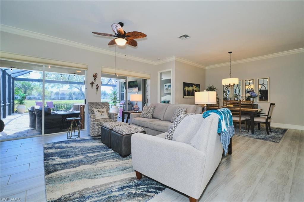 Living room with a sunroom, light wood-type flooring, ceiling fan, ornamental molding, and a chandelier