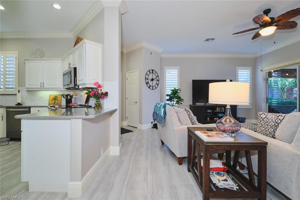 Living room featuring a ceiling fan, plenty of natural light, crown molding, and light wood finished floors