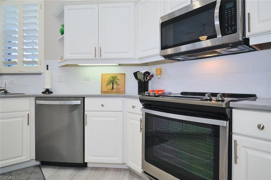 Kitchen featuring white cabinetry, stainless steel appliances, tasteful backsplash, and open shelves