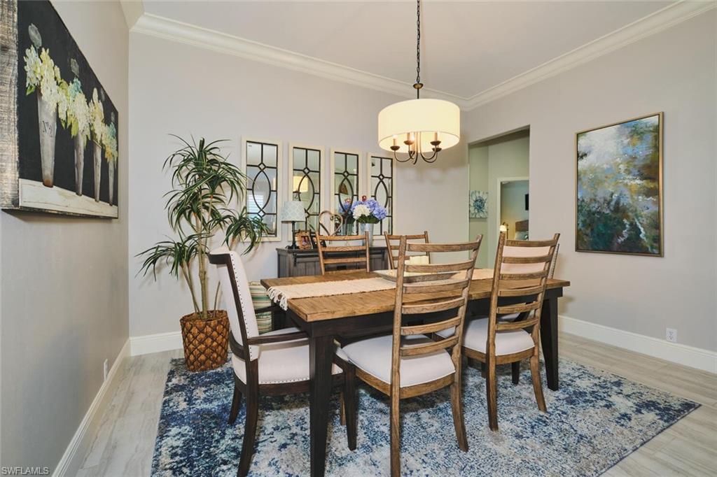 Dining area with ornamental molding, light wood-style flooring, and a chandelier