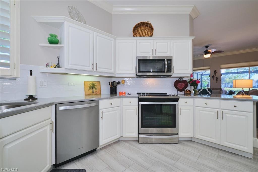 Kitchen with stainless steel appliances, white cabinets, ornamental molding, ceiling fan, and open shelves