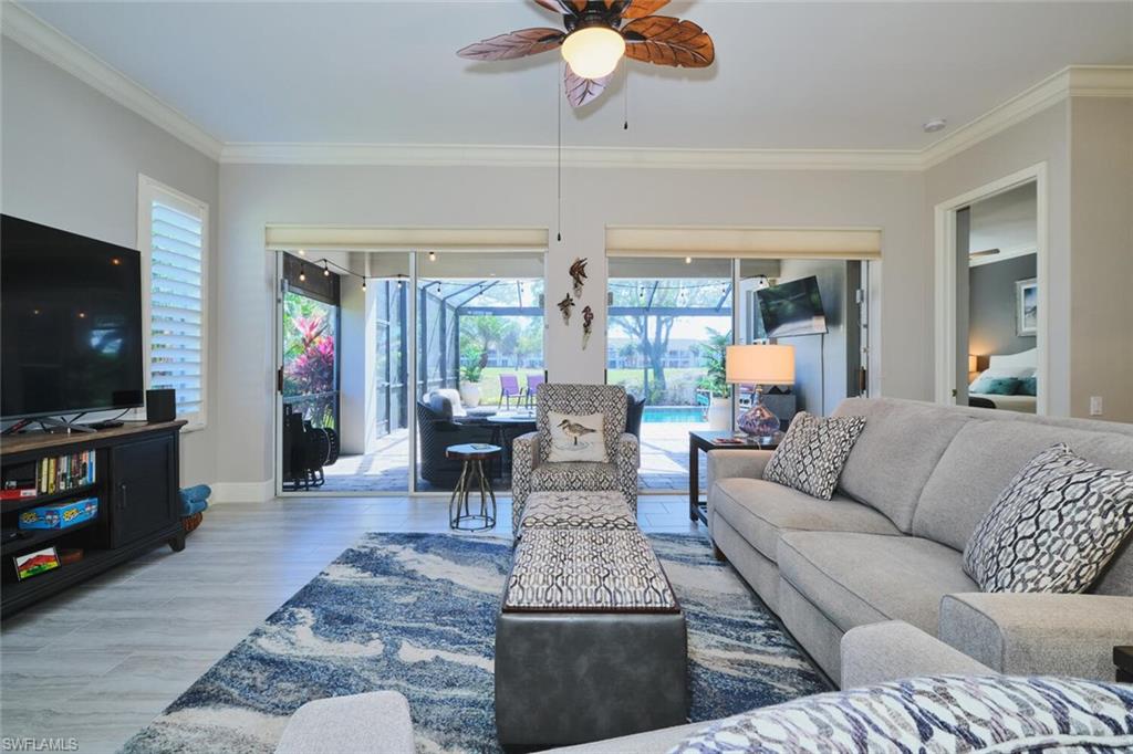 Living area featuring a ceiling fan, a sunroom, ornamental molding, and light wood-style floors