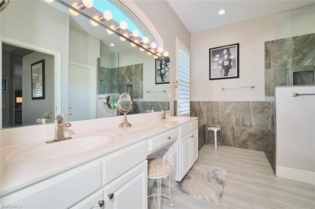 Bathroom with double vanity, tile walls, and walk in shower