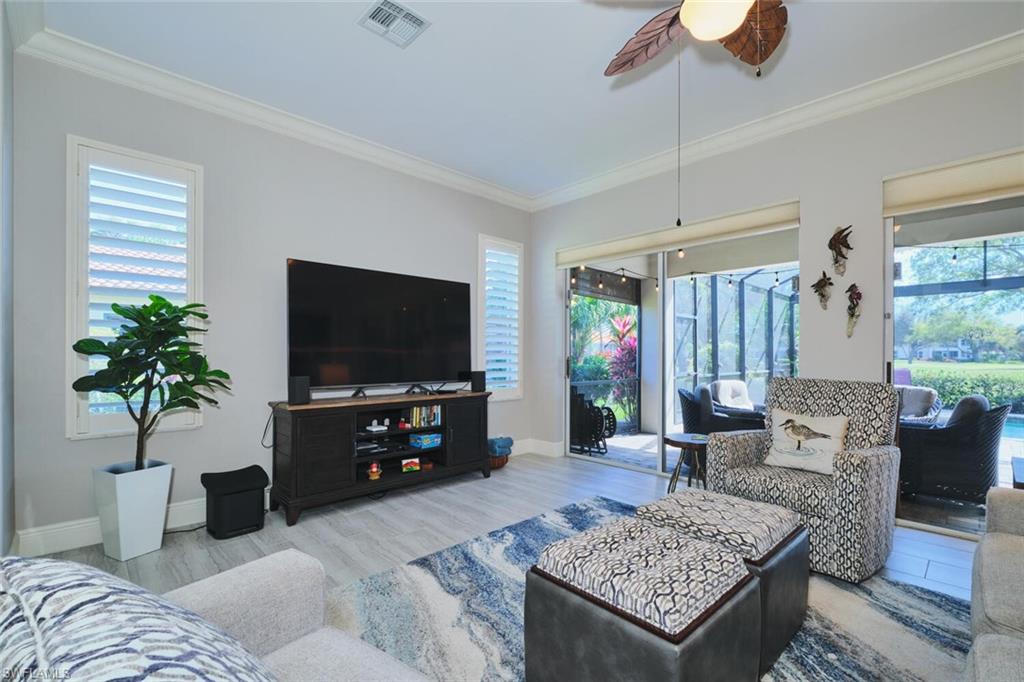 Living area with wood finished floors, plenty of natural light, ceiling fan, and crown molding