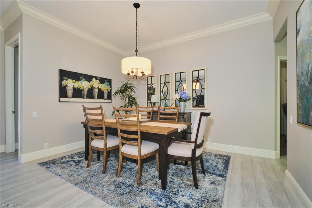 Dining room with crown molding, light wood finished floors, and hanging lights