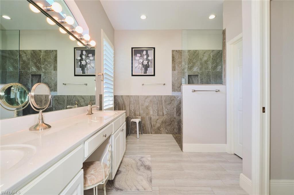 Full bath featuring double vanity, walk in shower, tile walls, and recessed lighting