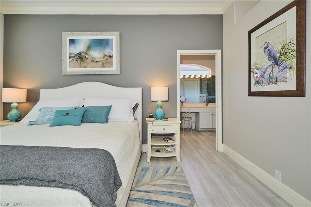 Bedroom with crown molding, wood finished floors, and connected bathroom