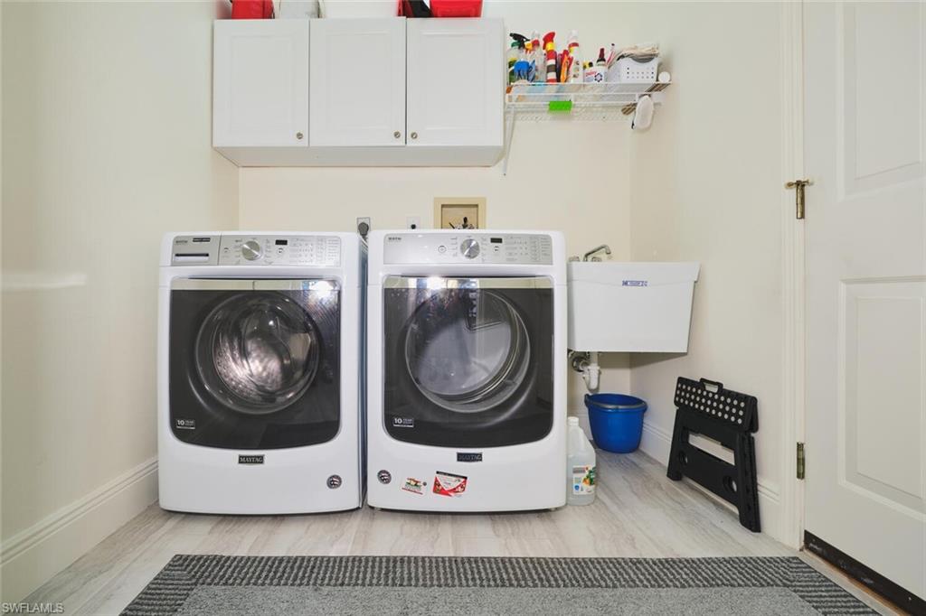 Laundry area featuring cabinet space, washing machine and clothes dryer, and light wood-style floors