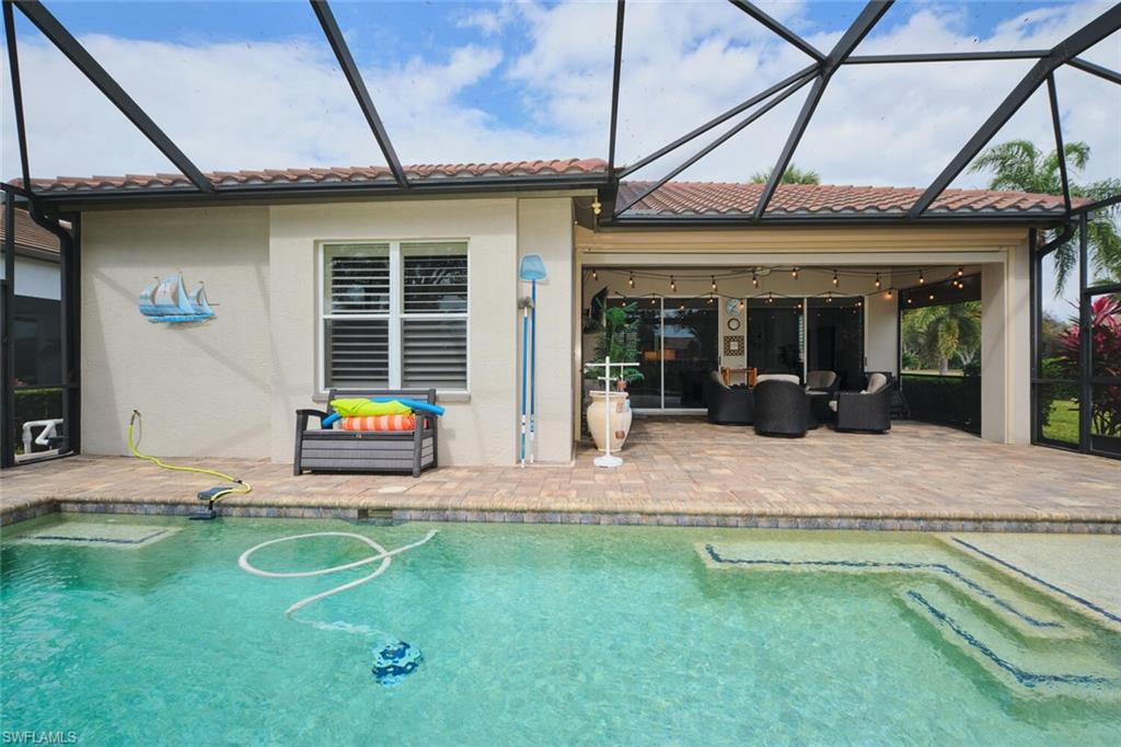 Back of house featuring a sunroom, an outdoor pool, a patio, and a tiled roof