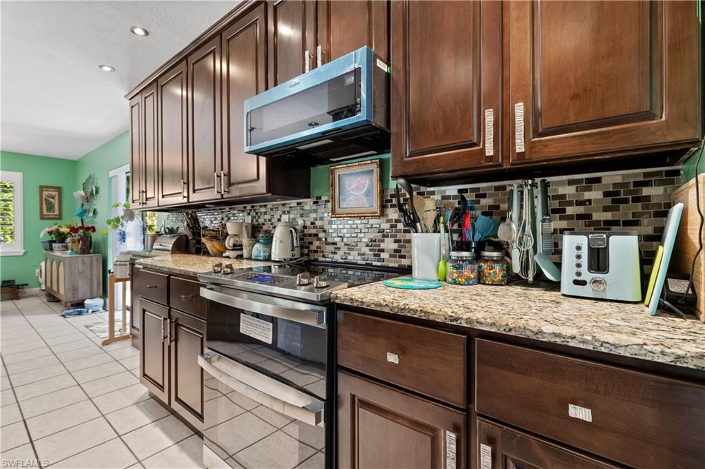 View of Granite Kitchen with Tiled Backsplash, High End Stainless Appliances and Crown Molded Cabinetry to Ceiling [Note attractive Desinger Cabinetry Hardware]