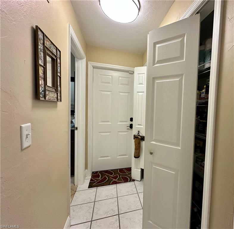 View of the "Hallway" with Two Shelved Closets [one used as Pantry and Second used as Linen/Storage]. View also doorway to the Side Load Two Car Garage and Left Doorway to the East Ensuite Bathroom.