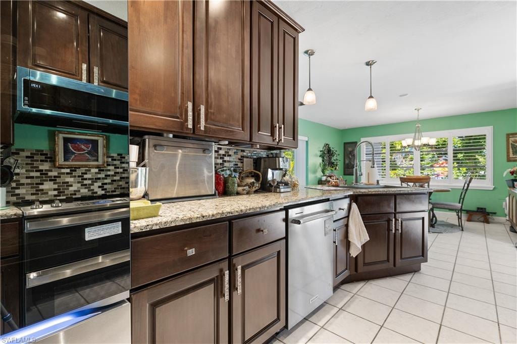 View of Granite Kitchen with Tiled Backsplash, High End Stainless Appliances and Crown Molded Cabinetry to Ceiling [Note attractive Designer Cabinetry Hardware]