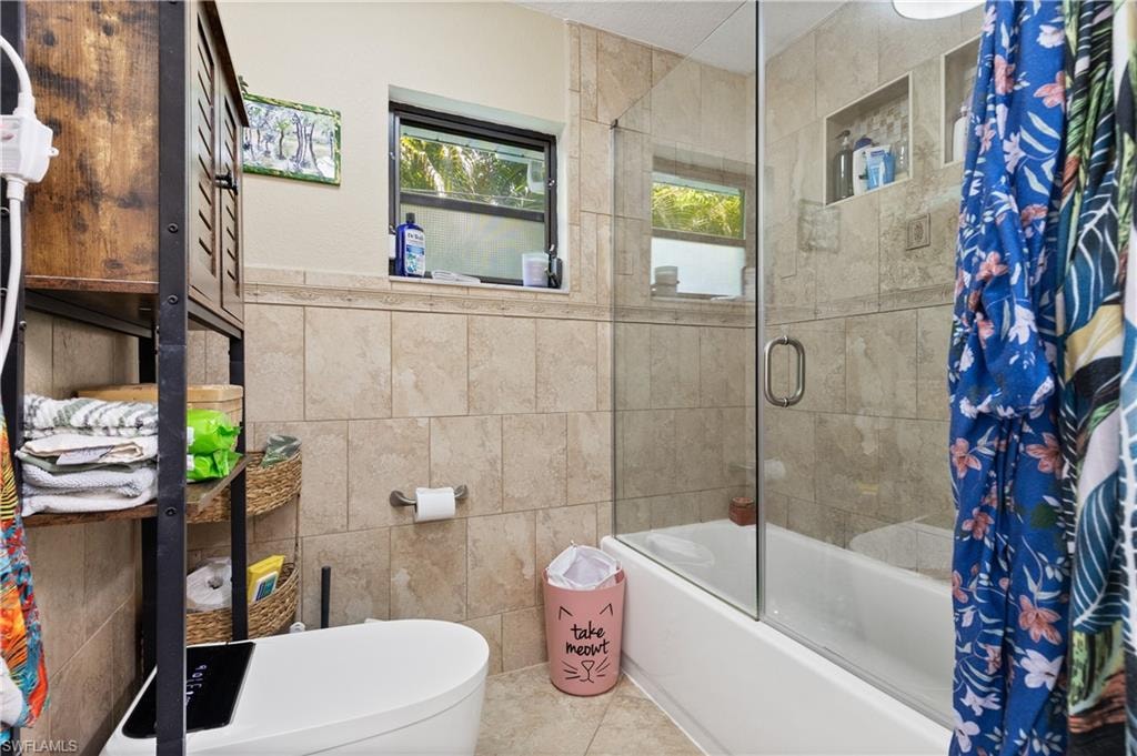 View of the Eastside Bath Glass Doored Combo Tub/w/Handheld Shower with Decorative Tiling to ceiling, with two InCut Shelving and "Heated Intelligent Toilet."