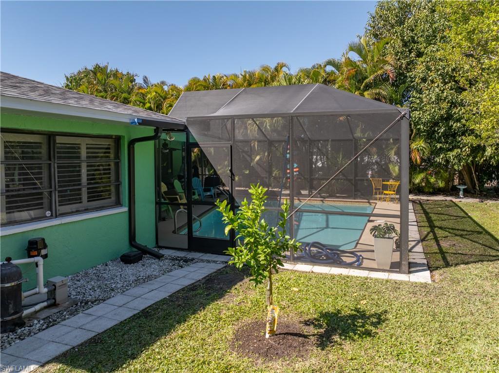 View of Rear Dining Room Plantation Shutters and New 2025 Pool Screen Enclosure [Note Newly Landscaped/Mulched Back Yard with Fruit Trees, Ice Cream Banana Tree, Key Lime Tree, Meyers Lemon and Navel Orange Tree and with Mulched Perimeted Beds