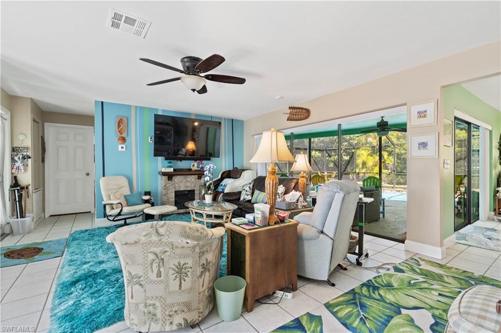 View of Sunlit Tiled Living Room with Doorway to East Ensuite, its Remote-Controlled Faux-Fireplace under Wall Mounted TV and Pocked Slider to Lanai/Pool Deck . . . also on pic right the Slider from Kitchen/Dining Room to Lanai/Pool Deck.
