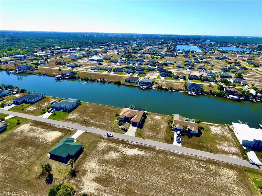 Aerial view of property and surrounding area featuring a large body of water and nearby suburban area