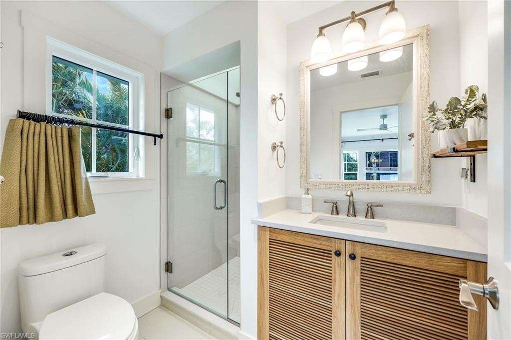 Bathroom featuring visible vents, a stall shower, toilet, and vanity