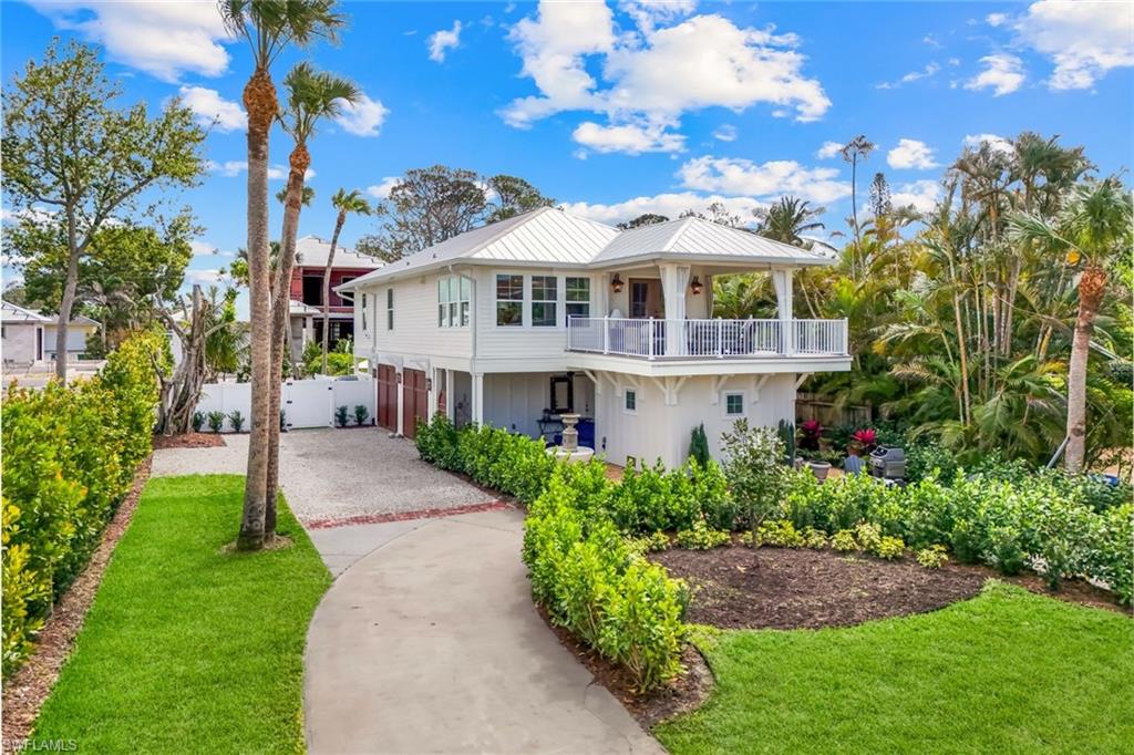 View of front of home with driveway, fence, a front yard, an attached garage, and a balcony