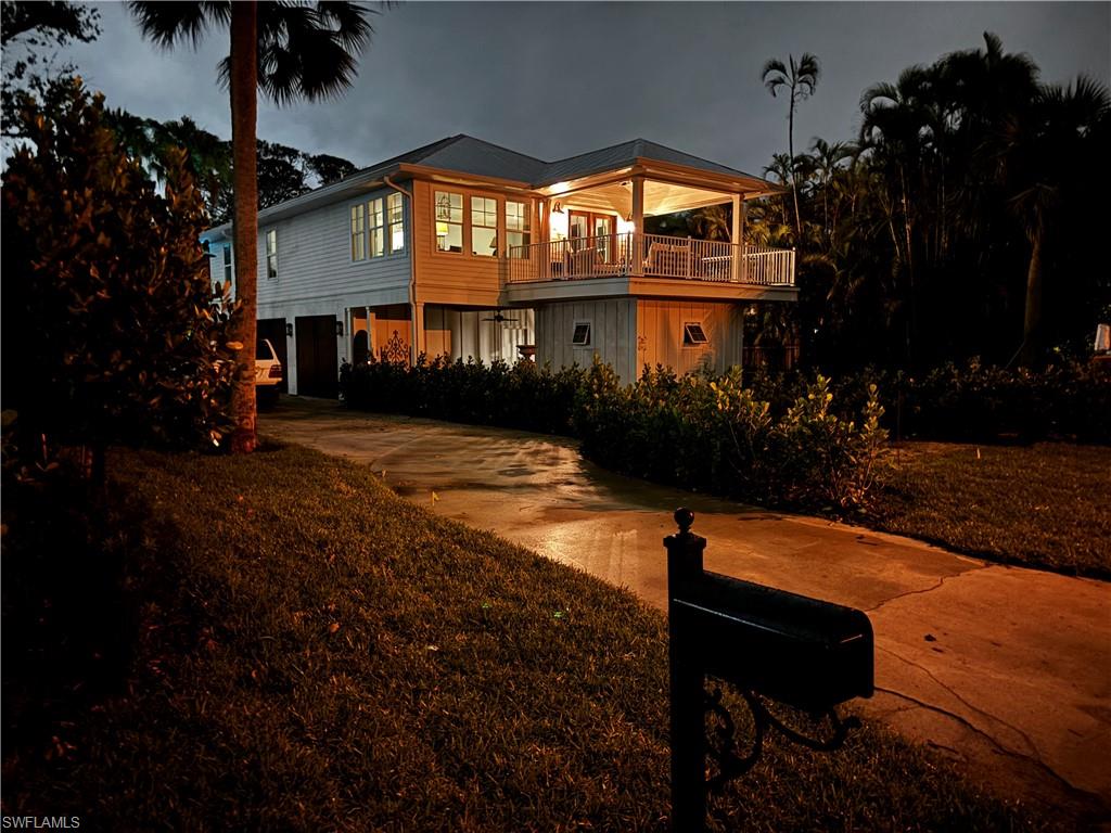 Back of house with concrete driveway and a balcony