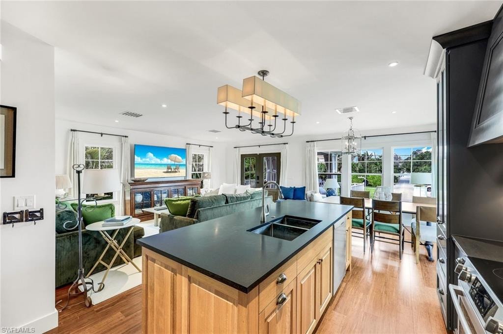 Kitchen featuring dark countertops, visible vents, light wood-style flooring, stainless steel appliances, and a sink