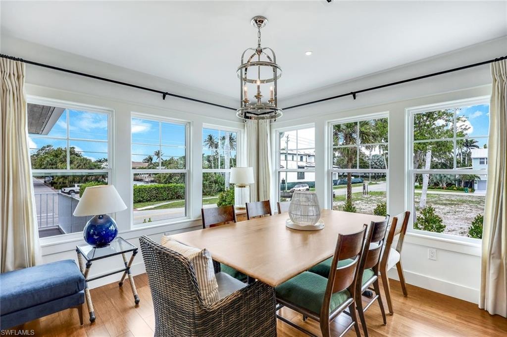 Dining area featuring light wood finished floors, plenty of natural light, and an inviting chandelier
