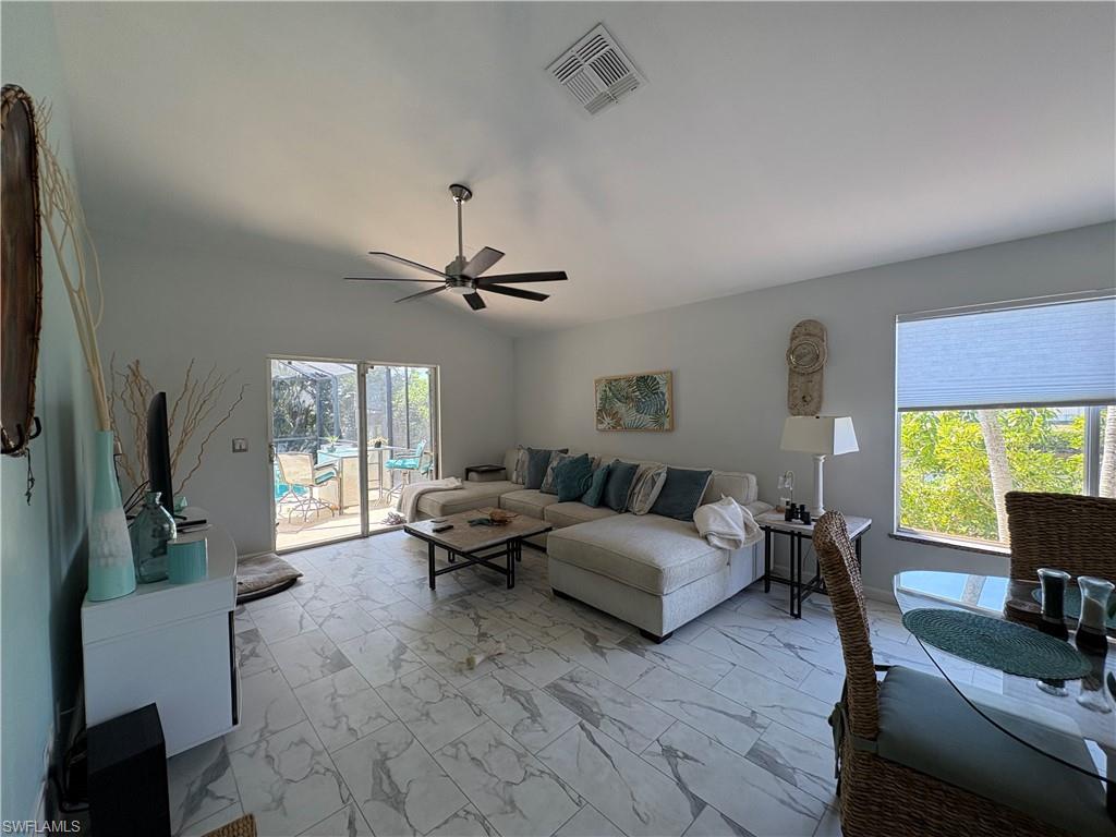 Living room with light marble finish flooring, lofted ceiling, and a ceiling fan