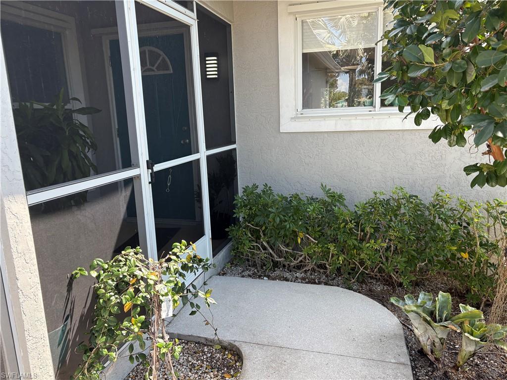 View of exterior entry with stucco siding and a sunroom