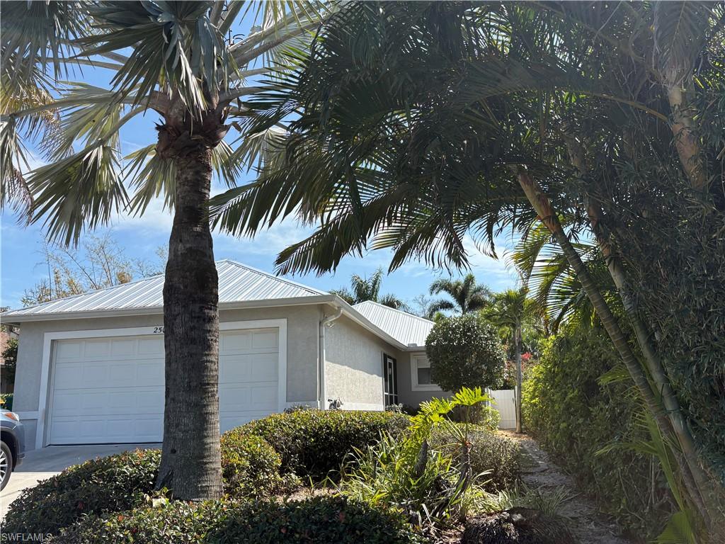 View of property exterior featuring stucco siding, a garage, driveway, and a metal roof