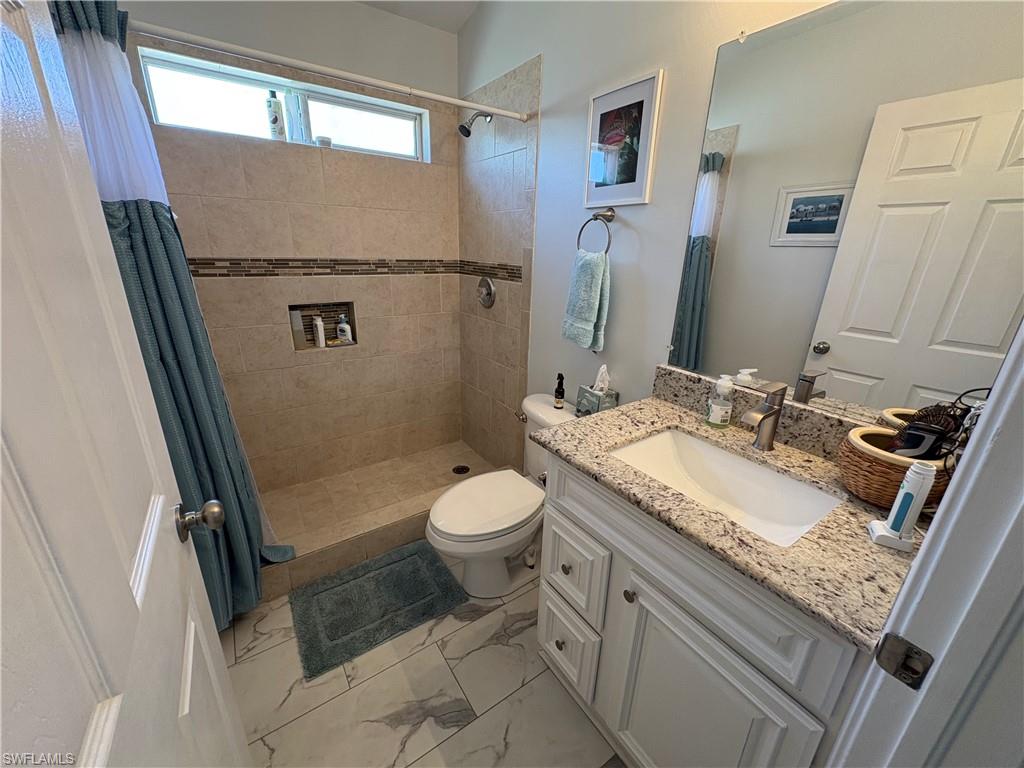 HALL Bathroom featuring vanity, a stall shower, and light marble finish floors