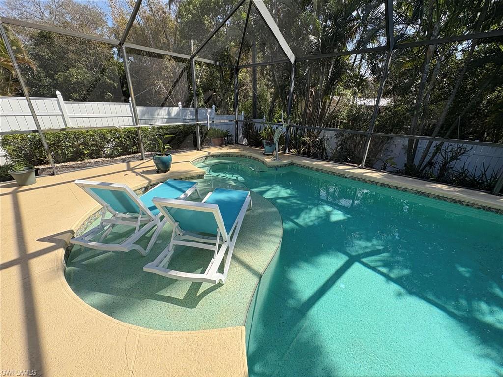 View of pool featuring a fenced backyard, a lanai, a sunroom, and patio surround
