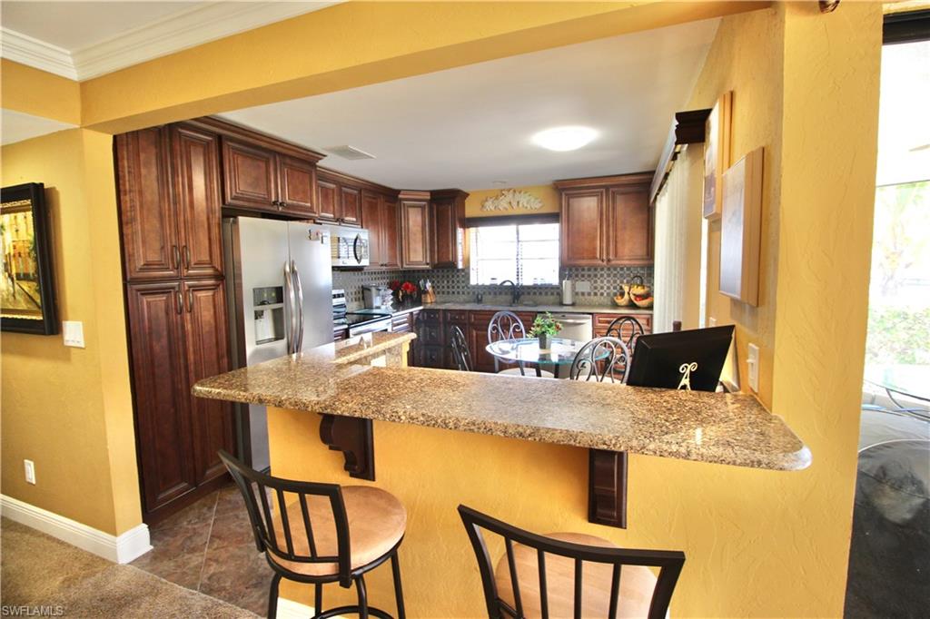Kitchen featuring a peninsula, stainless steel appliances, a kitchen breakfast bar, decorative backsplash, and granite countertops