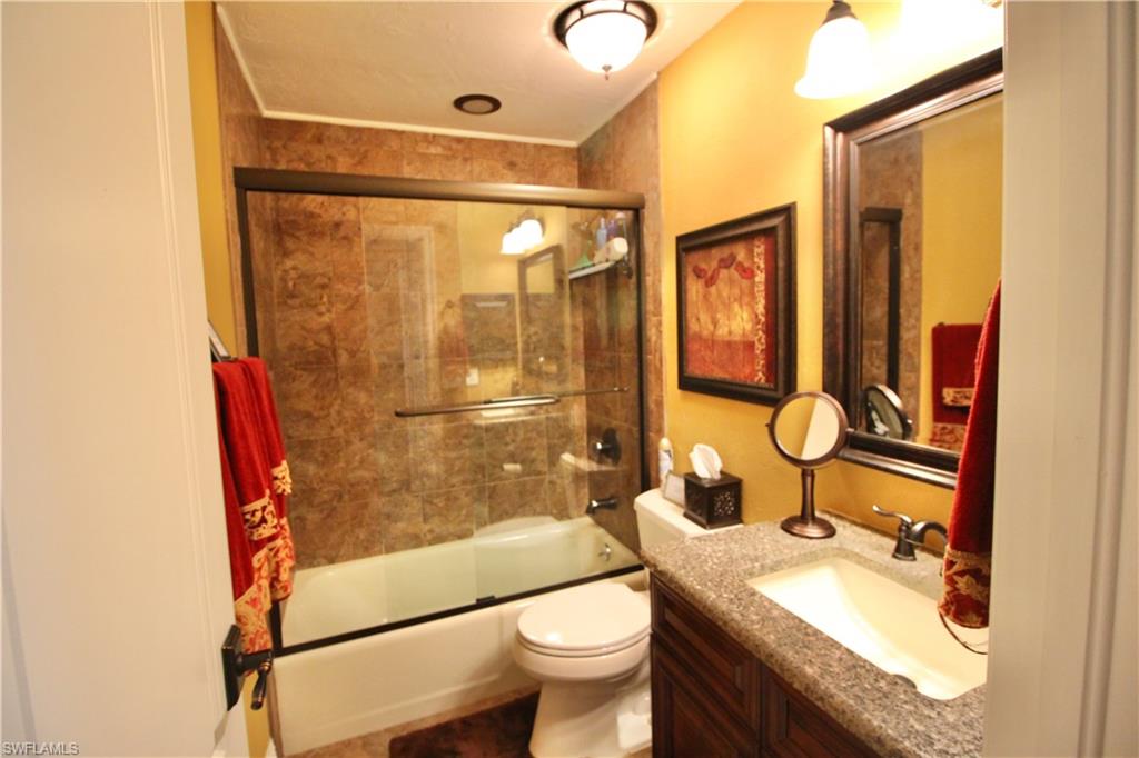 Full bath featuring vanity and combined bath / shower with glass door, granite countertop