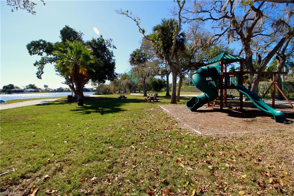 Community playground with a yard and a water view and picnic area