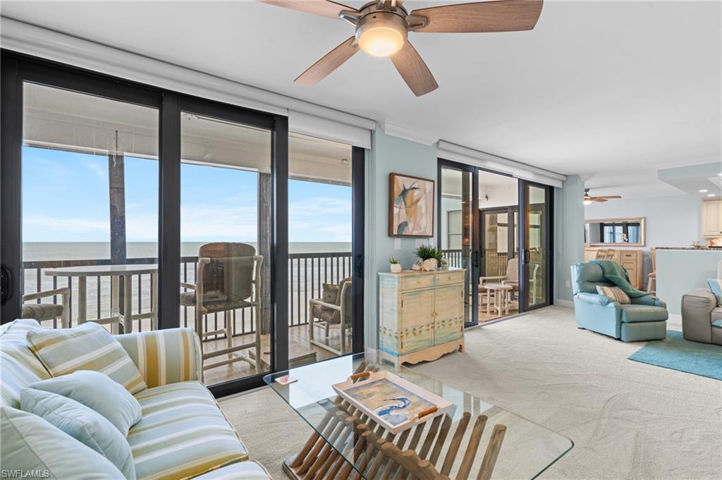 Carpeted living room with a ceiling fan, a water view, floor to ceiling windows, and ornamental molding