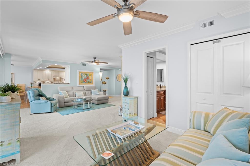Living room with crown molding, light colored carpet, and a ceiling fan
